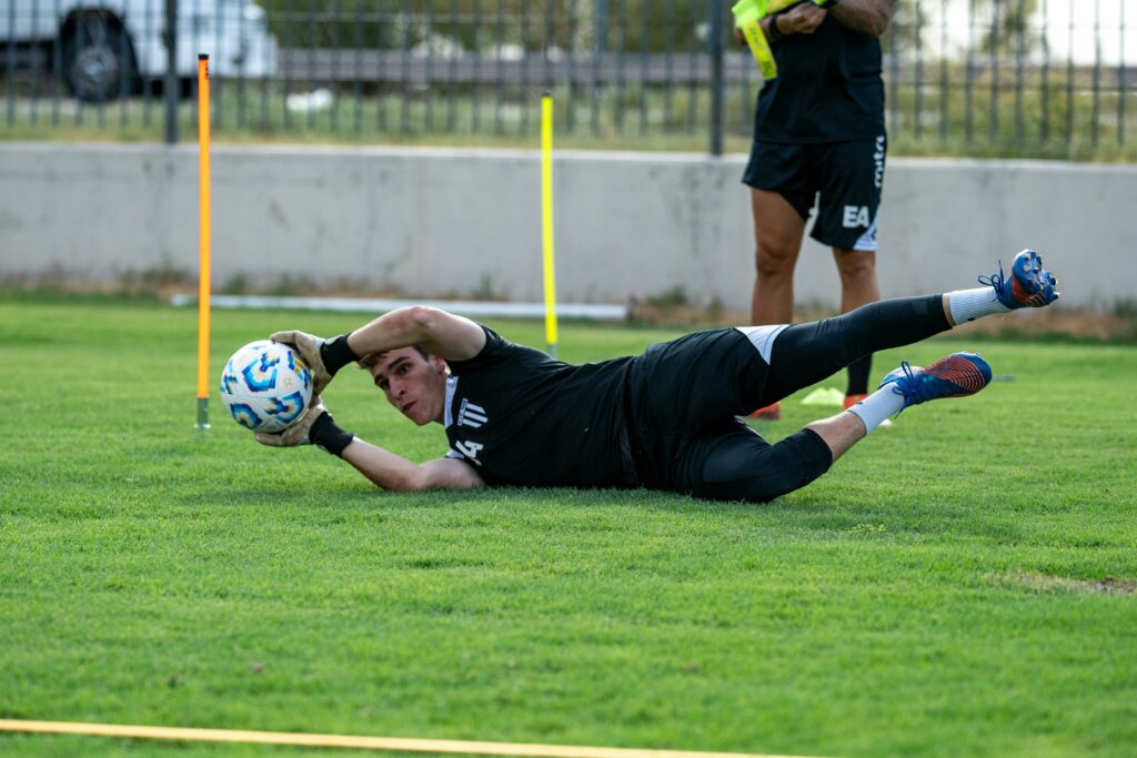 pexels photo 30585014 30585014 A young soccer goalkeeper dives to catch a ball during training on a grassy field.