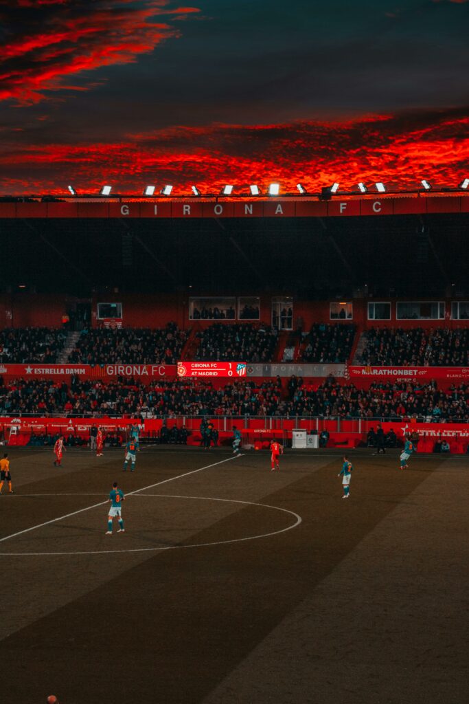 pexels photo 1657328 1657328 Dramatic evening soccer game at Girona FC stadium with vibrant red sky and intense play.